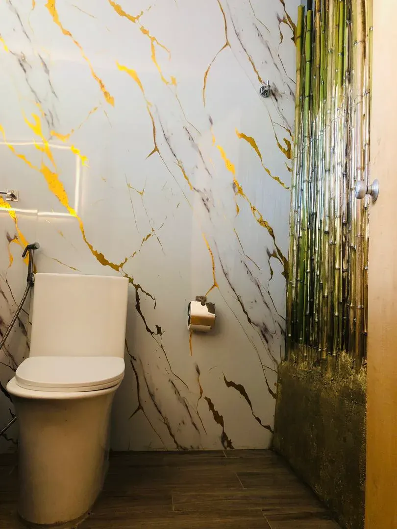 Baño revestido en mármol blanco de vetas doradas, con panel de bambú natural iluminado en la pared lateral