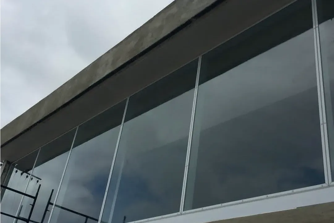 Vista lateral del cerramiento de vidrio de la planta alta, con perfilería de aluminio de sección estrecha