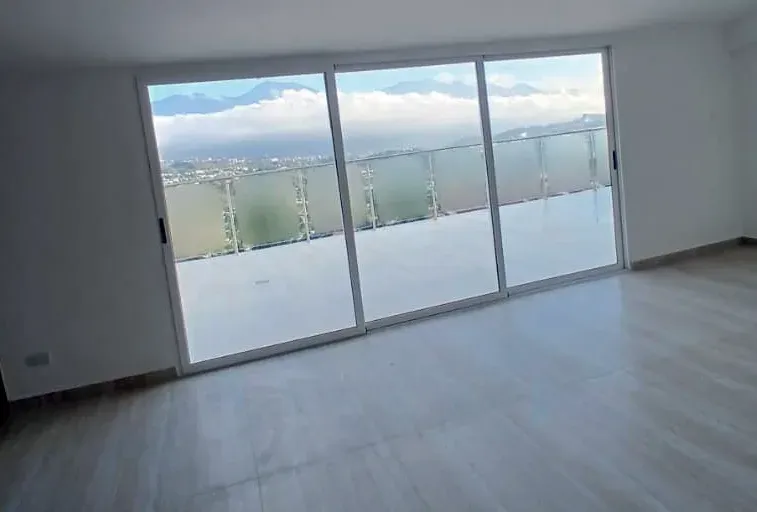 Habitación terminada con piso de madera clara y ventanal hacia la montaña