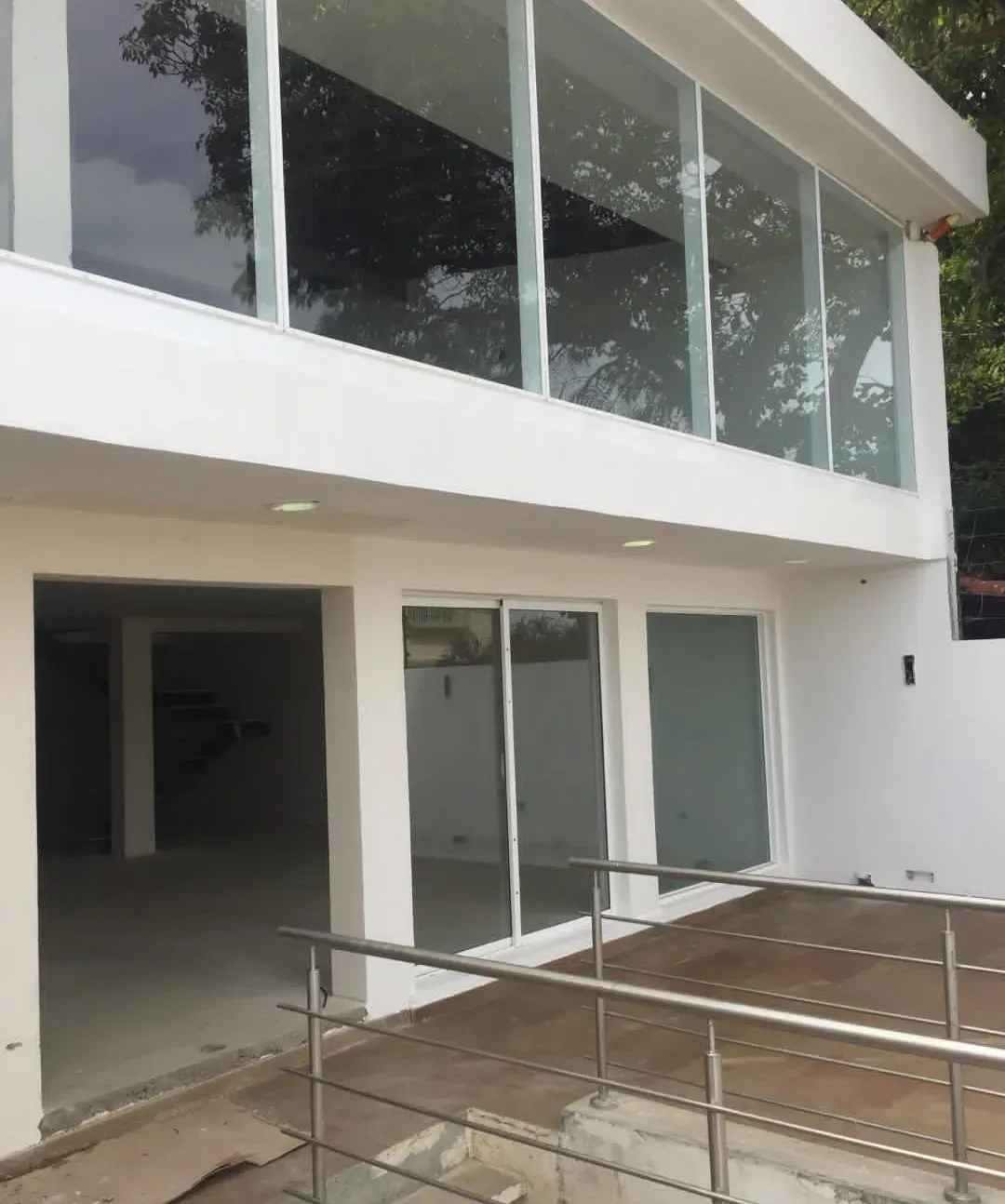 Terraza de la vivienda con columnas blancas de doble altura y piso de baldosa