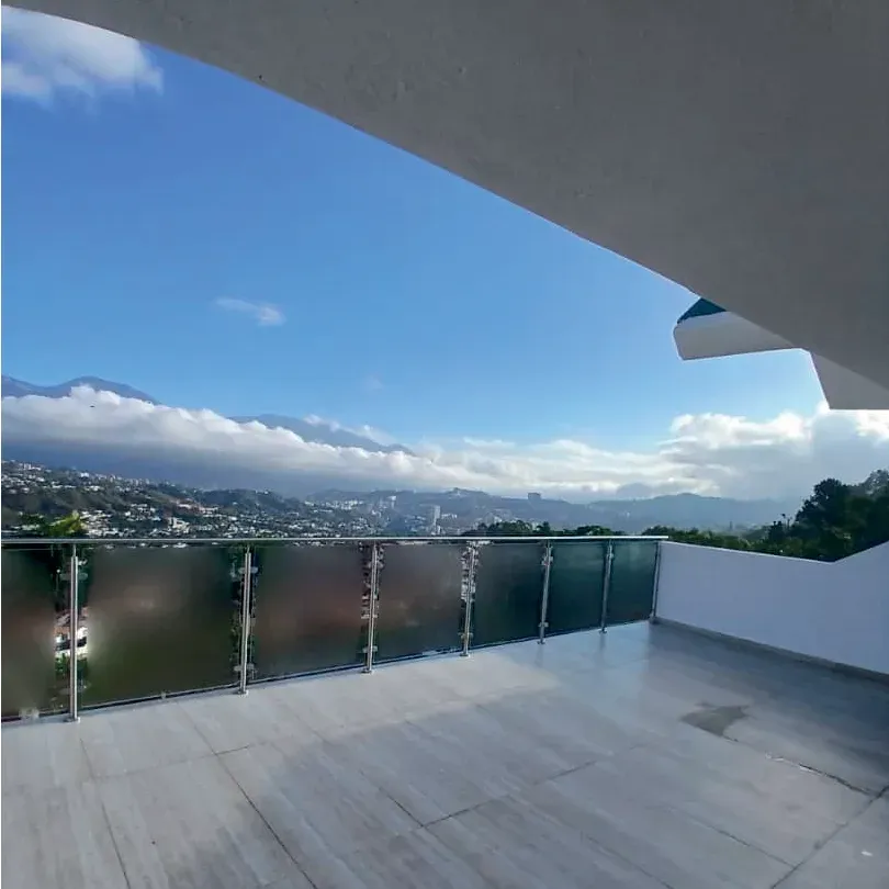 Terraza de la Quinta Edith con baranda de vidrio y vista abierta al valle de Caracas